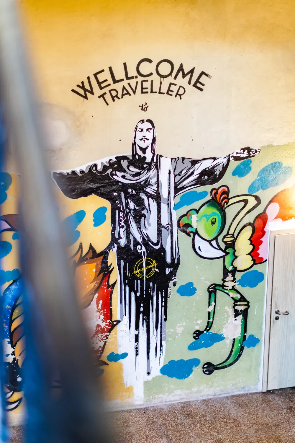 Falfestmény a lépcsőházban „Welcome traveller” felirattal